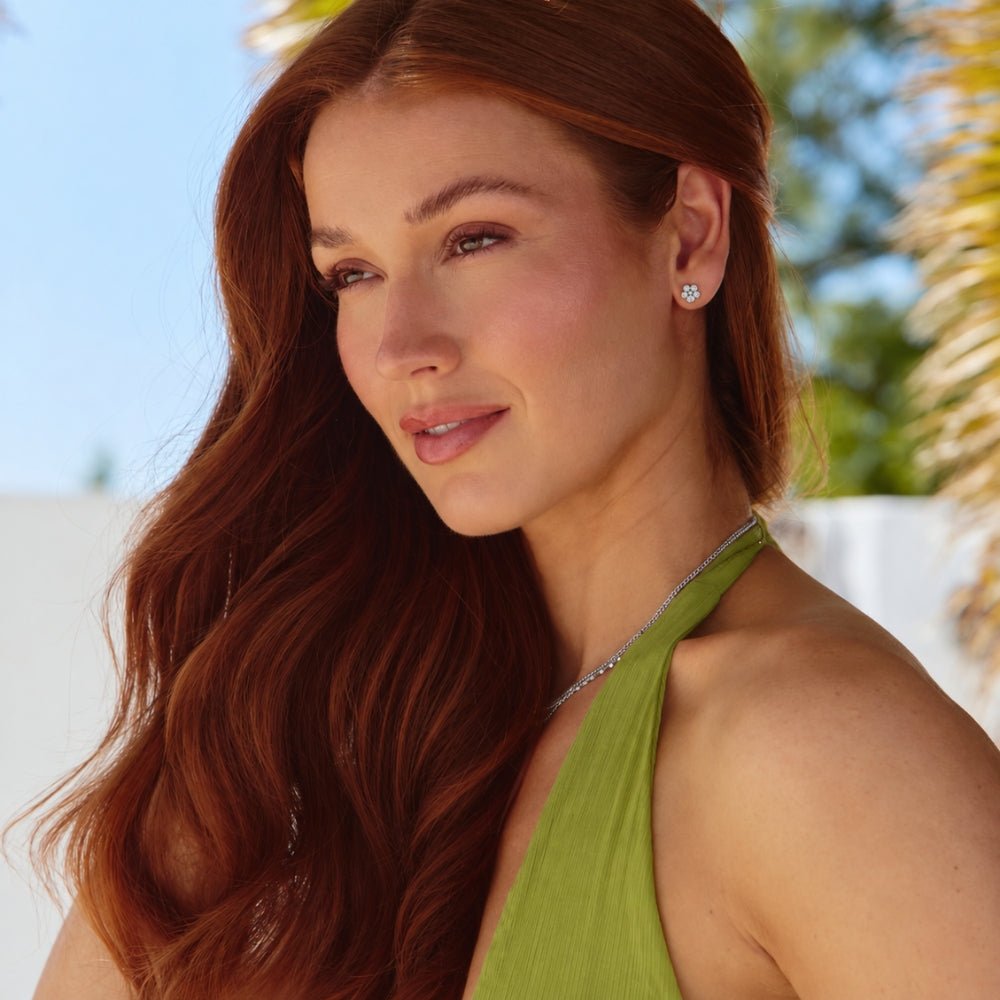 Five Petal Bloom Silver Earrings, worn on a model with red hair and a green halter top
