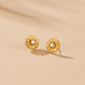 Golden Sunflower Stud Earrings, a pair of gold flower studs with clear centre stones on beige